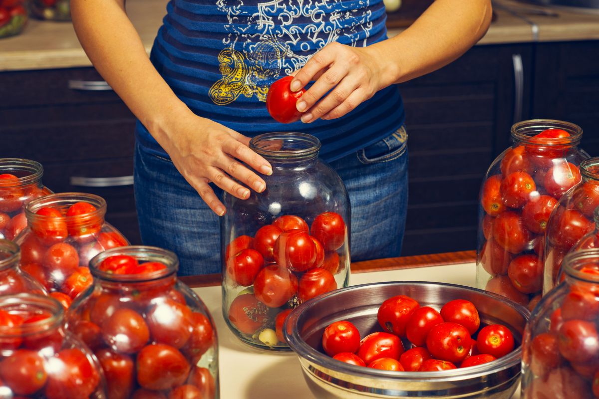 woman placing whole tomatoes in jars
