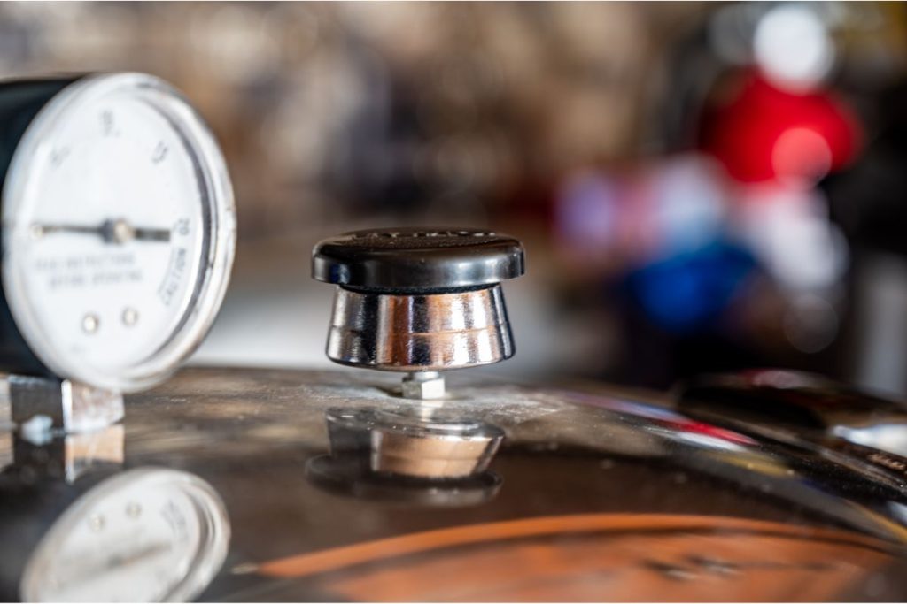 Photo showing up close photo of a dial gauge pressure canner with a weight