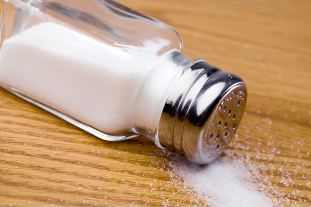 Salt shaker spilling table salt on table