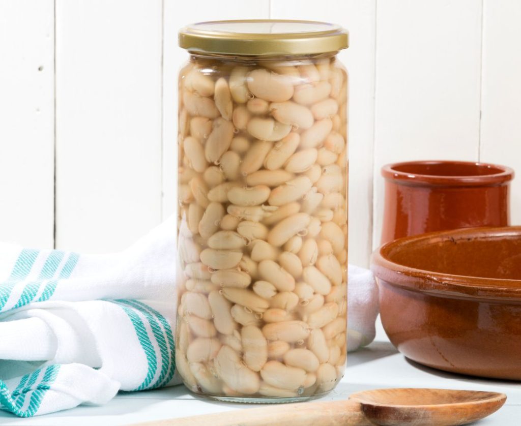 Pressure-canned white beans in a tall canning jar on a table