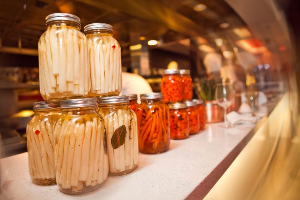 Pickled white asparagus in canning jars on countertop in a restaurant