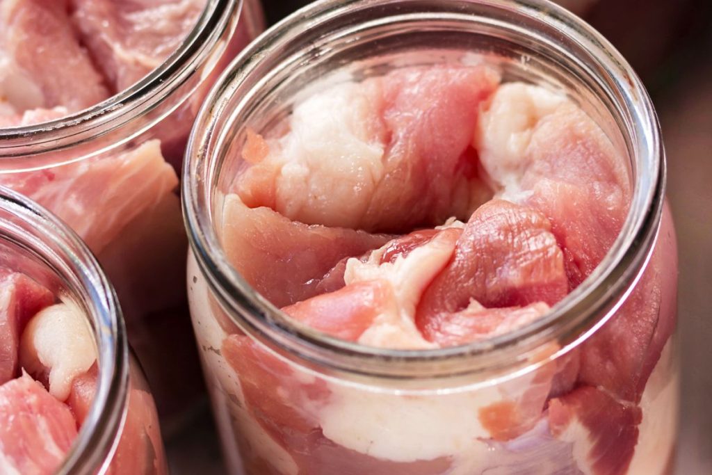 Raw packed pork meat in canning jars