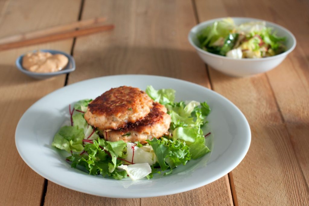 Salmon patties on bed of lettuce on a plate