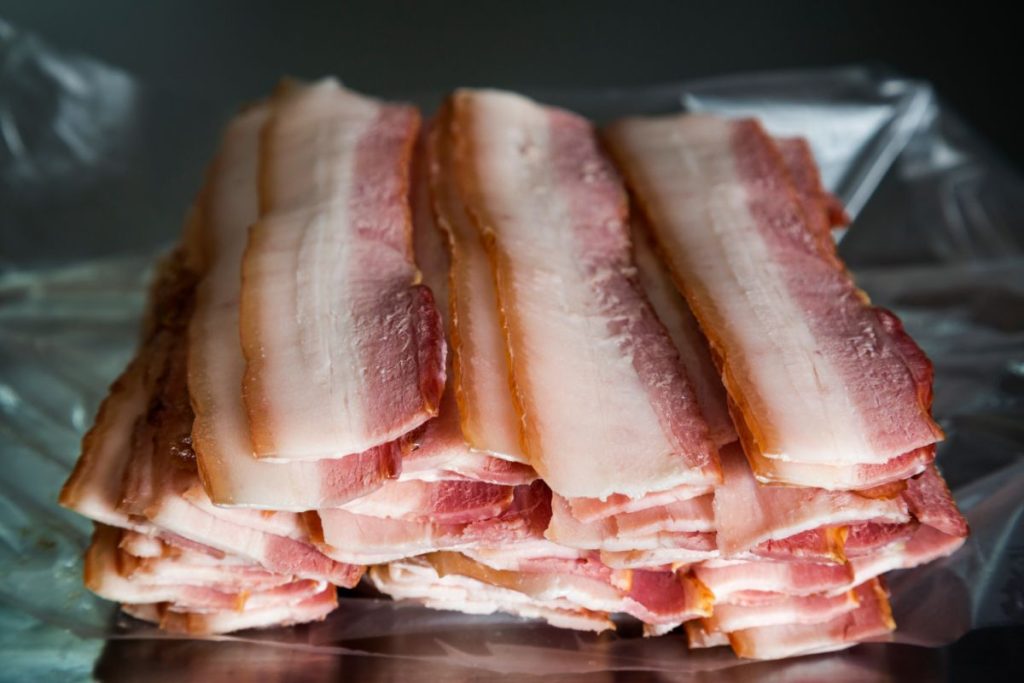 Thick cut bacon strips stacked on top of tin foil