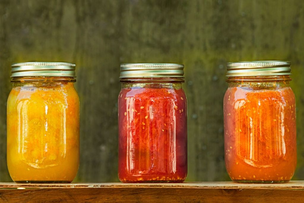Three jars with different colors of canned tomatoes; yellow, red, and orange.