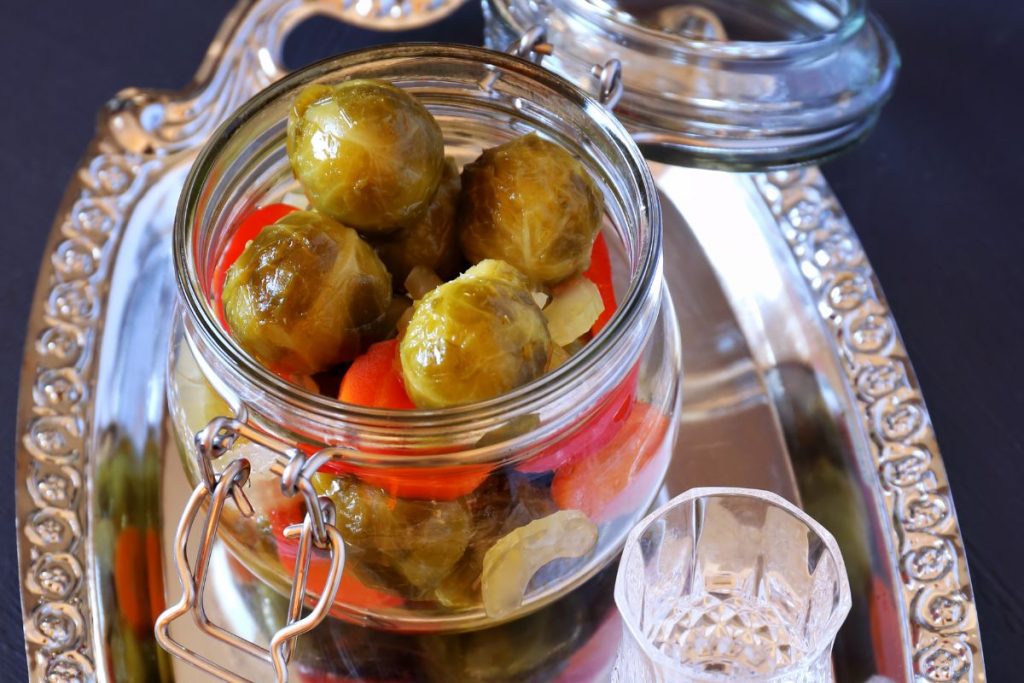 Pickled Brussels sprouts on a silver platter in a canning jar