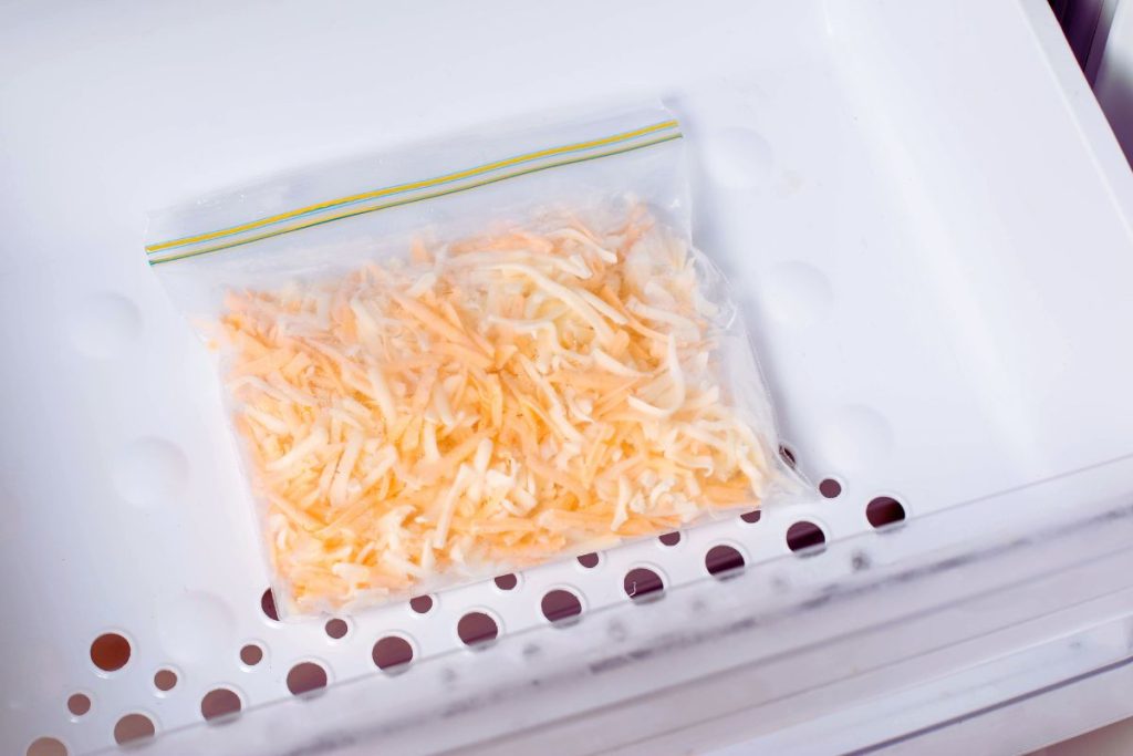 Frozen, shredded cheese in a plastic bag inside freezer drawer