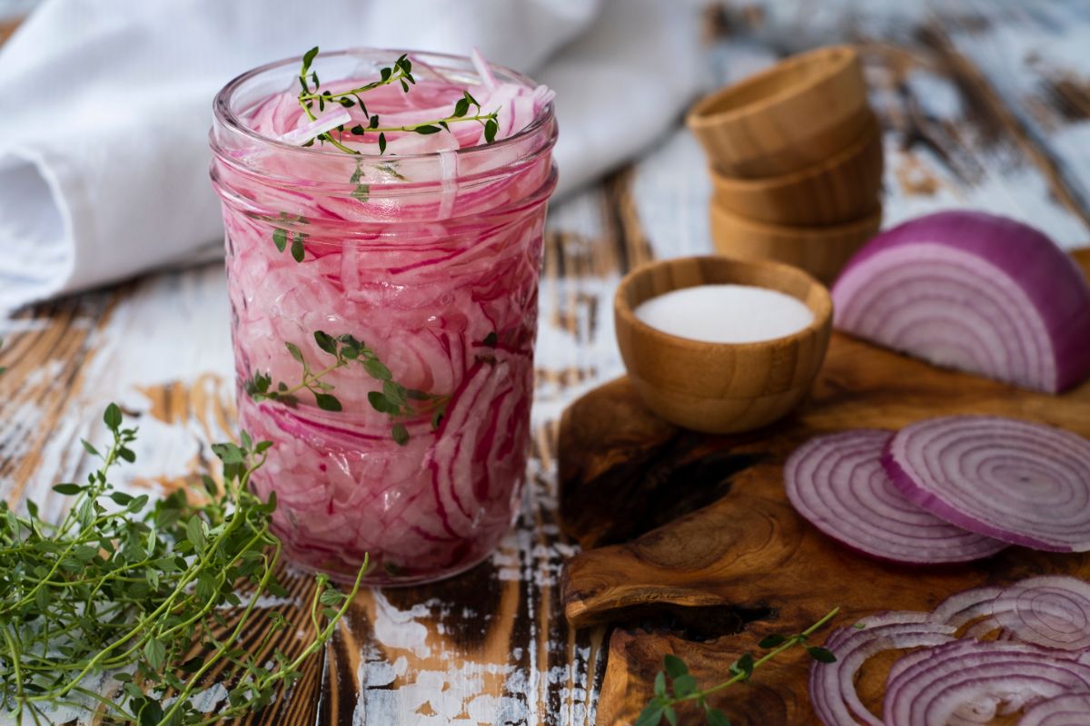 Jar of pickled red onions with herbs