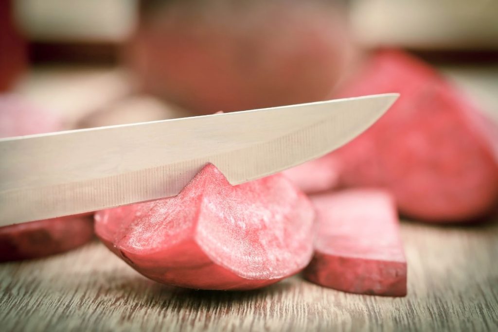 A knife slicing a beet into quarters