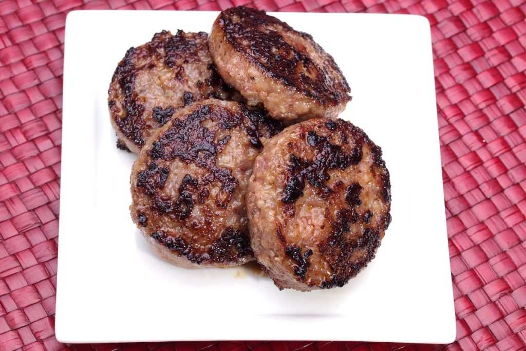 Browned breakfast sausage patties on white plate