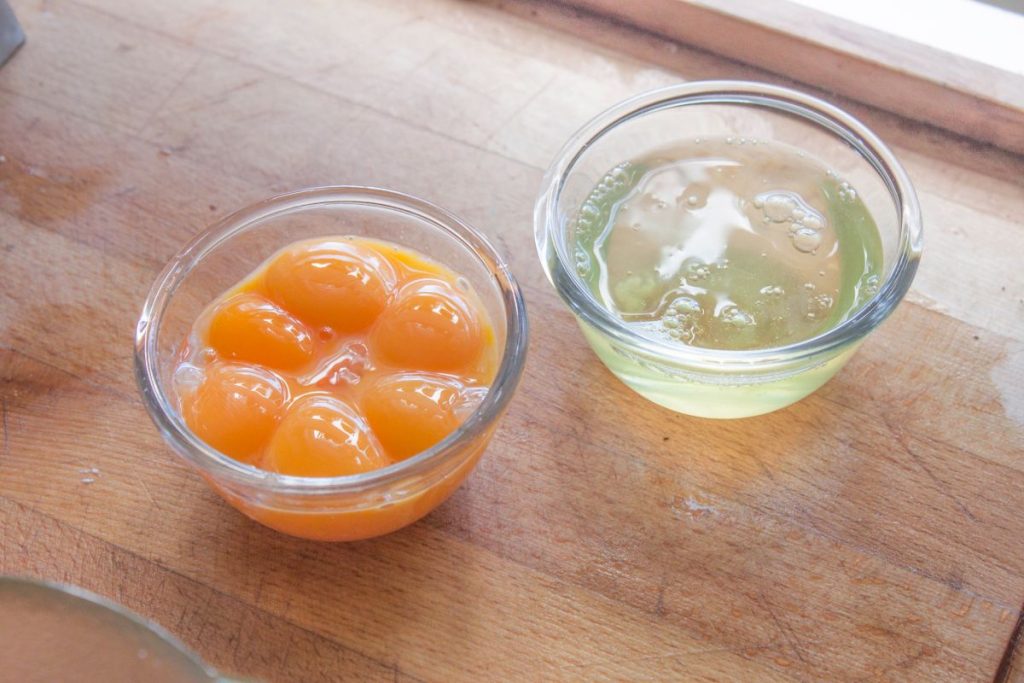 Two small glass bowls with one containing only egg whites and the other only egg yolks