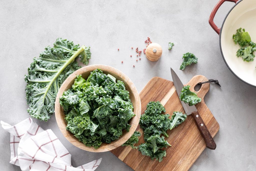 Trimming kale on a cutting board with a knife