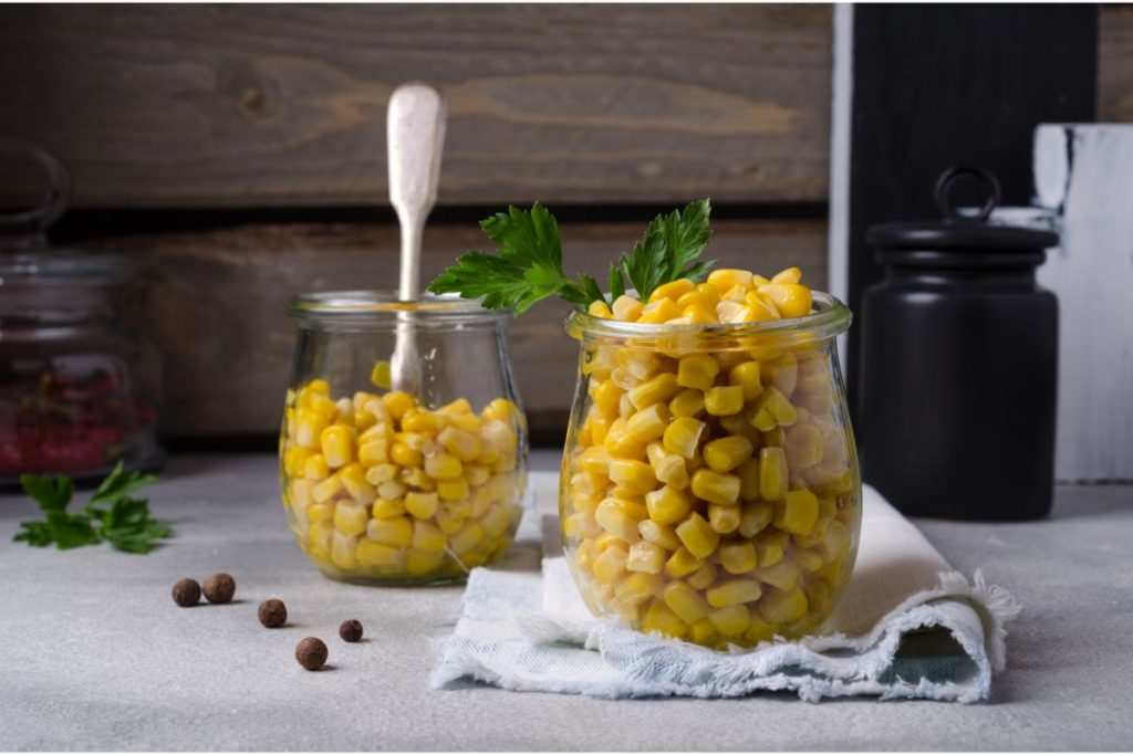 Canned corn kernels in open Mason jars