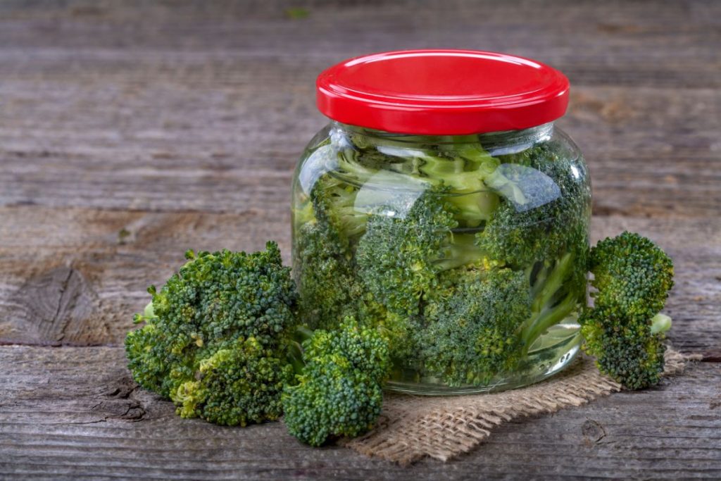 Broccoli in a Mason jar surrounded by broccoli florets