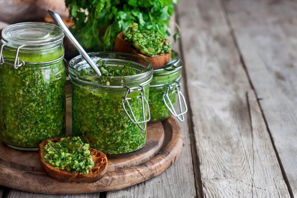 Homemade cilantro pesto in airtight glass jars on table