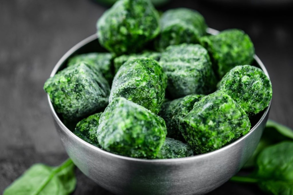 Frozen spinach cubes in a metal bowl