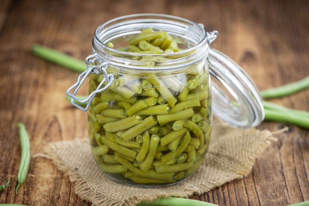 Open jar of cut green beans in canning liquid