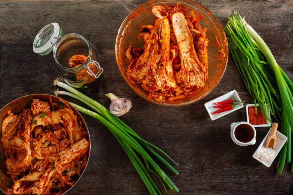 Table with kimchi ingredients and prepared kimchi ready to go into a canning jar