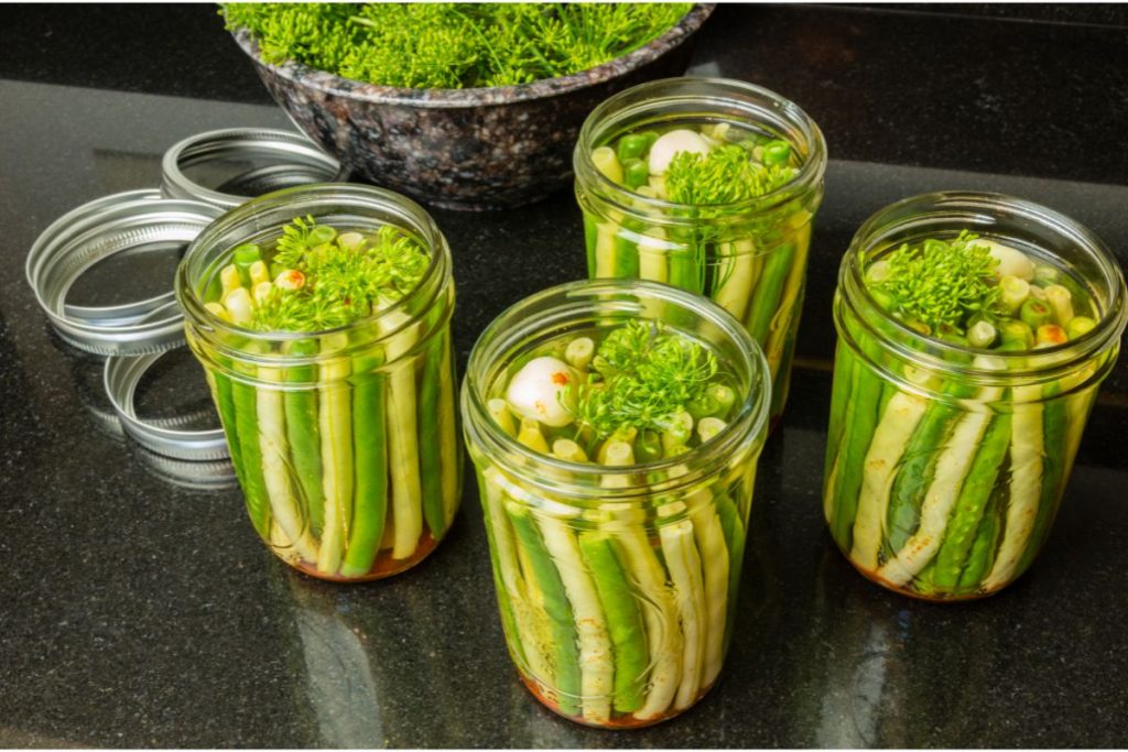Jars filled with raw green beans and wax beans and pickling spices