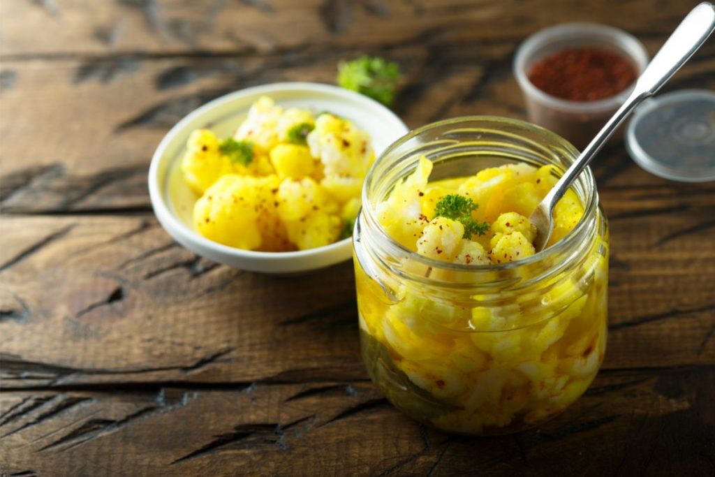 Open jar of pickled cauliflower with fork and bowl