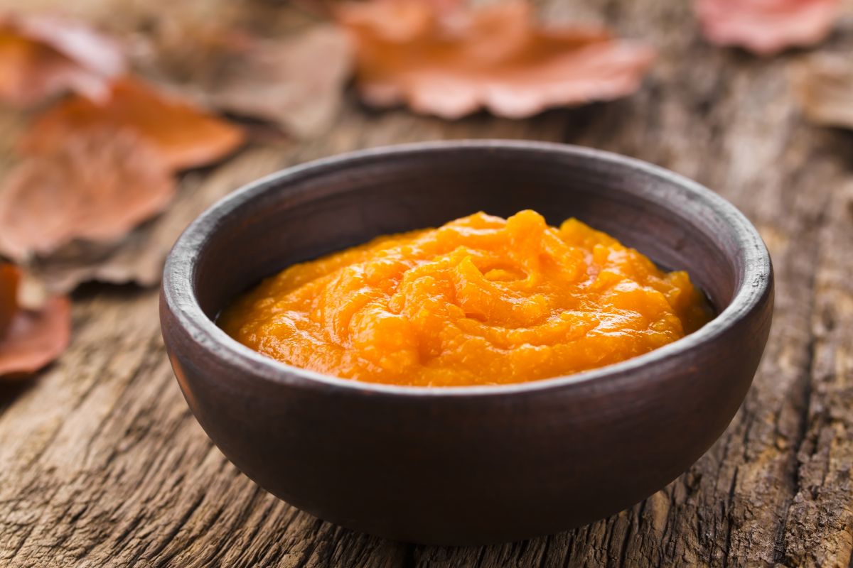 Bowl of pumpkin puree on a table with fall leaves