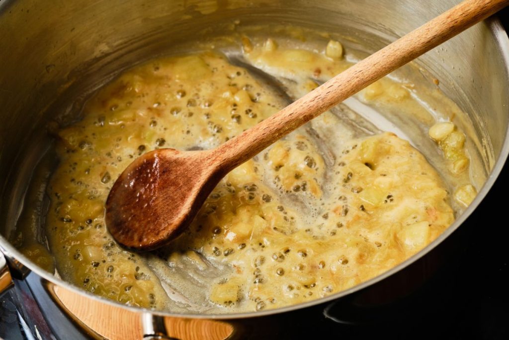 A large sauce pan with thickened fat and flour and a wooden spoon