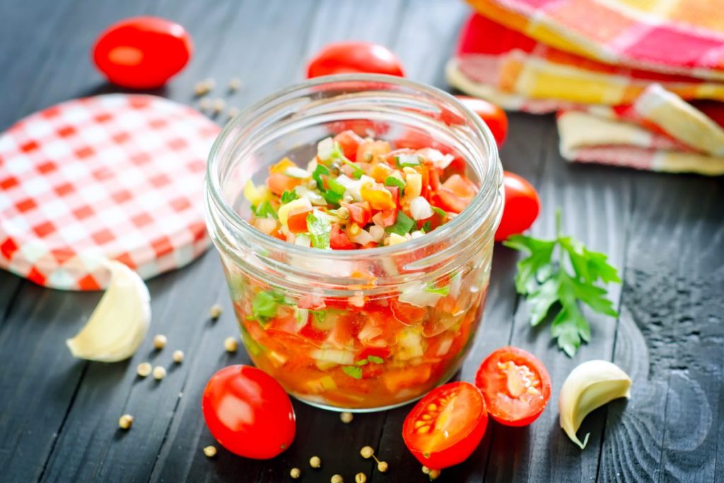 Open jar of salsa fresca surrounded by salsa ingredients