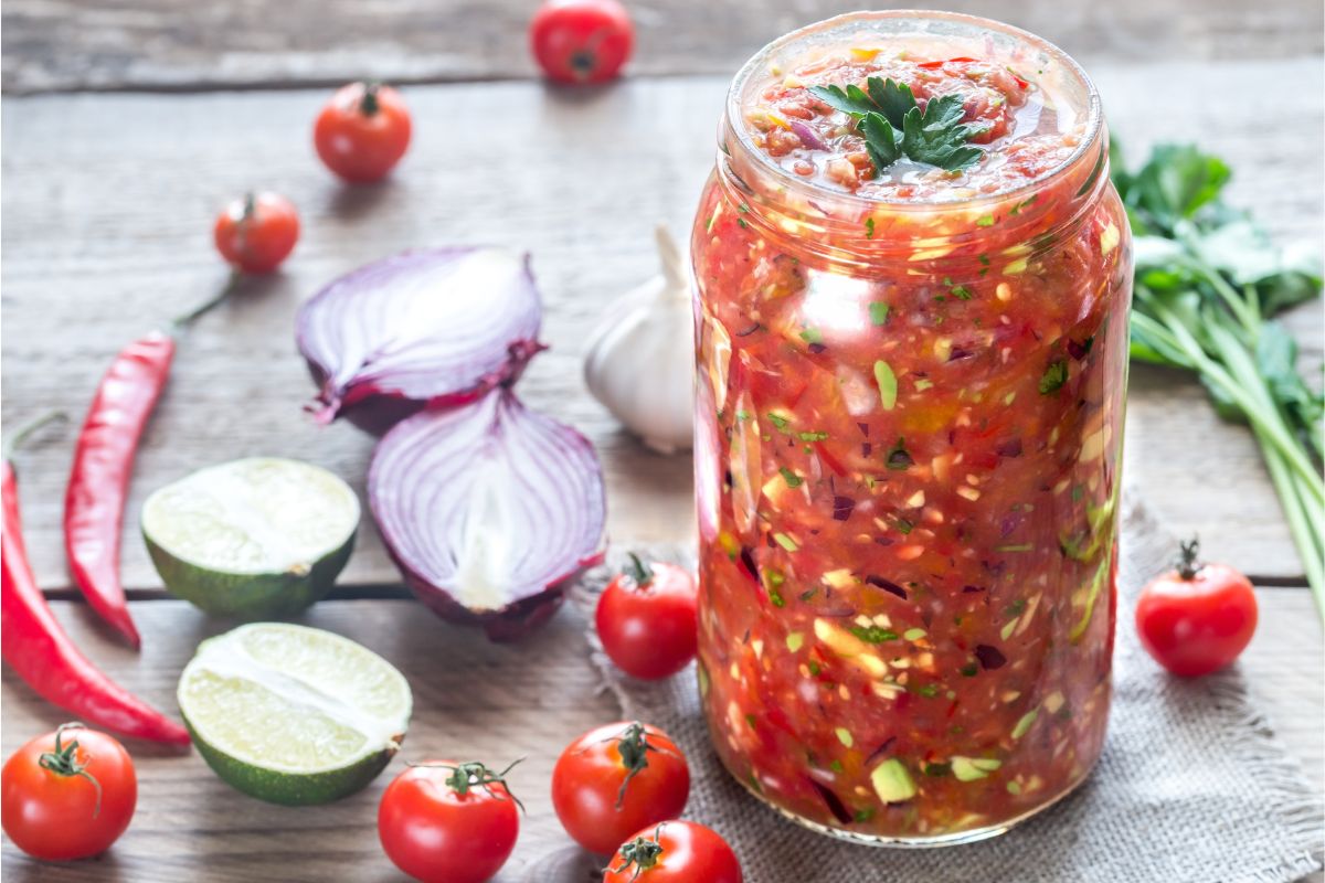 Open jar of salsa fresca with salsa ingredients