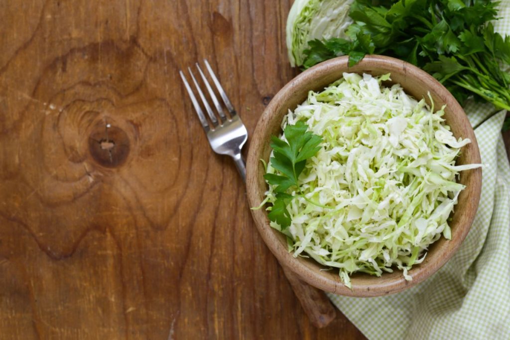 Bowl filled with green coleslaw and vinegar dressing