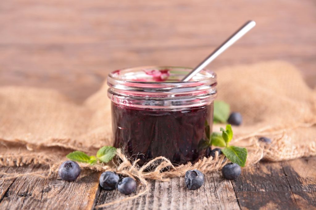 Blueberry pie filling in open jar with a spoon