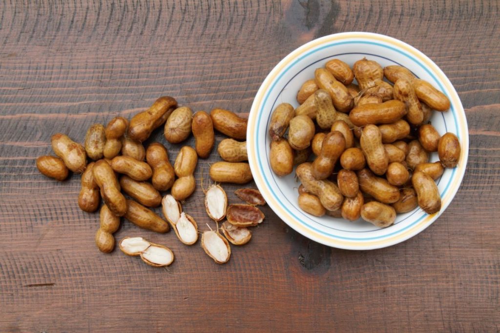 Bowl of boiled peanuts and stack of boiled peanuts split open on table