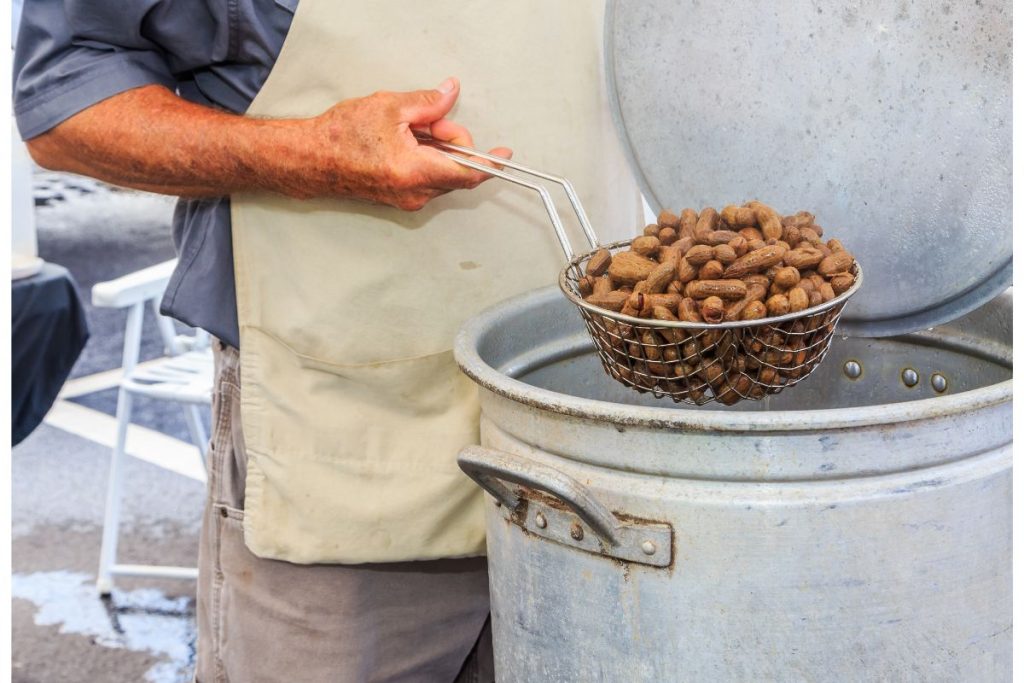 Man pulling boiled peanuts out of a large water tank