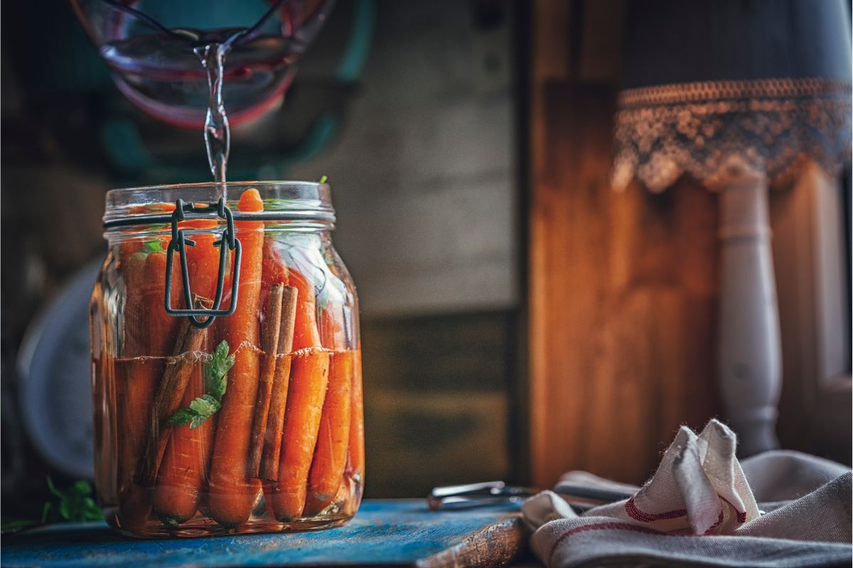 Pouring water into jar filled with carrots and spices