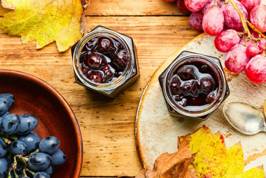 Canned grapes in jars in the fall with fall leaves on the table