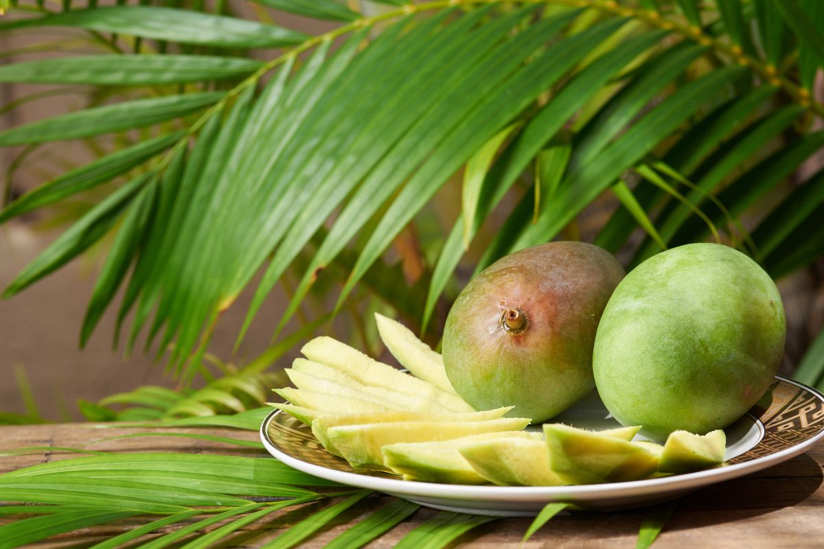 Green mango slices and green mangoes with palm leaves