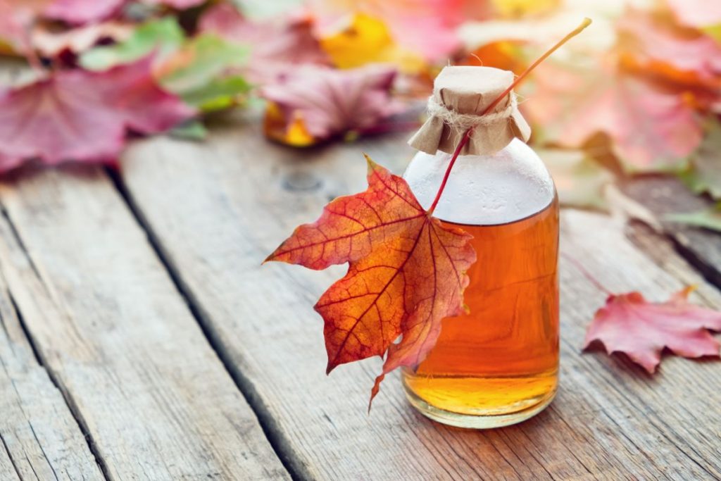 Bottle of maple syrup with maple leaves on a picnic table