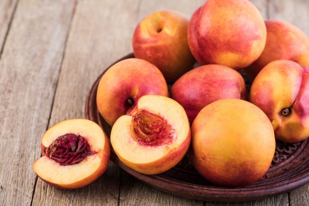 Fresh nectarines on a plate with one nectarine sliced in half