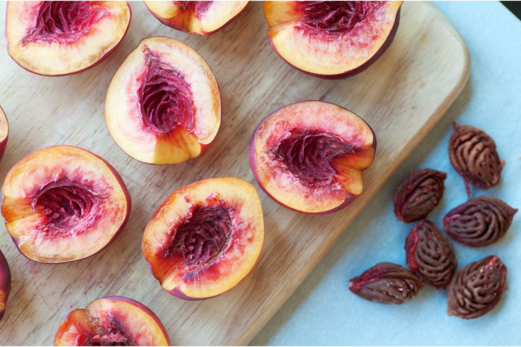 Cutting board with nectarines cut in half, pits removed and off to the side