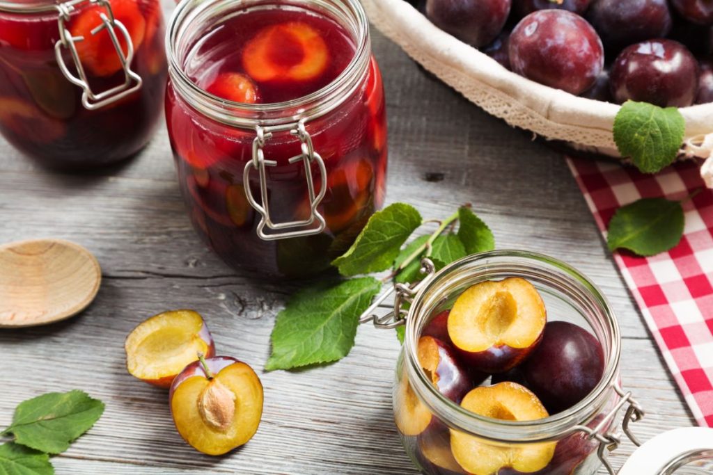 Unpeeled, halved plums with pits removed placed in canning jars