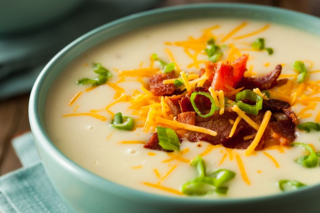 Bowl of loaded baked potato soup with cream, chives, cheddar cheese and bacon topping