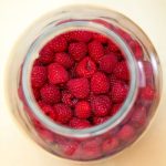 Top down view of whole raspberries in canning jar