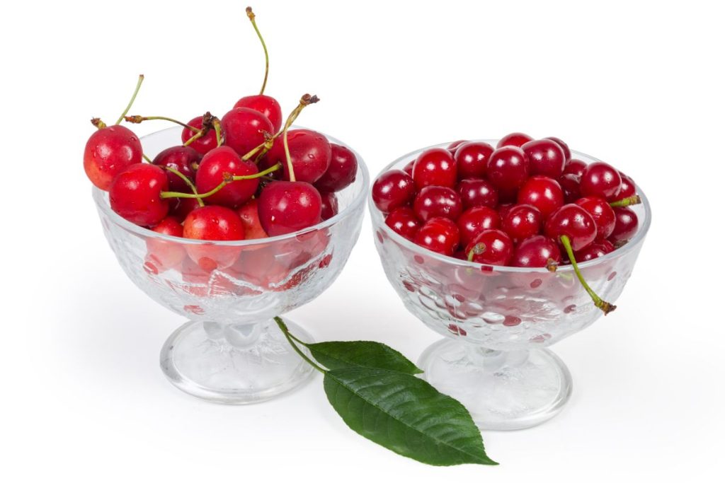 Two bowls side by side, one with sour cherries and one with sweet cherries